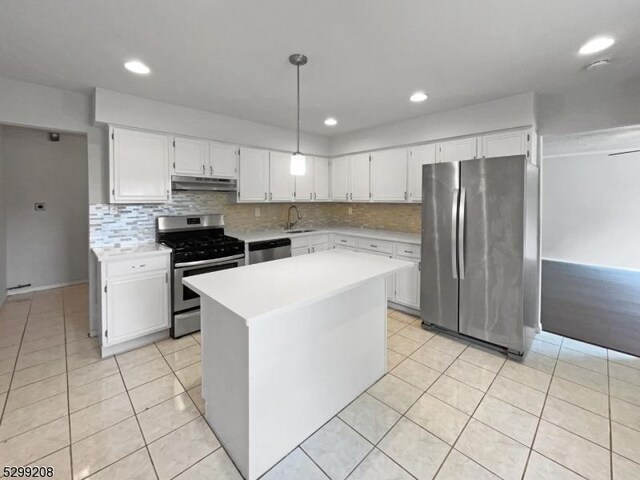 kitchen with light tile patterned floors, a kitchen island, stainless steel appliances, decorative light fixtures, and sink