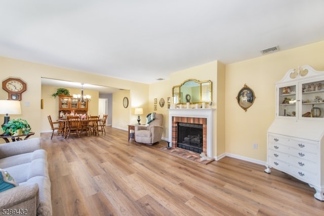 living room featuring a notable chandelier, a fireplace, and light hardwood / wood-style floors