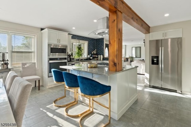 kitchen with a center island, dark stone countertops, white cabinetry, and appliances with stainless steel finishes