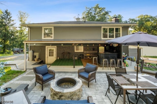 back of house with exterior bar, a fire pit, and a patio area