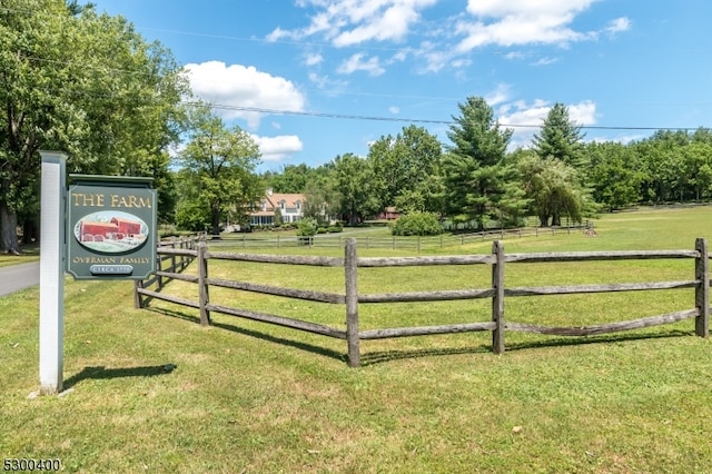 view of gate with a lawn and a rural view