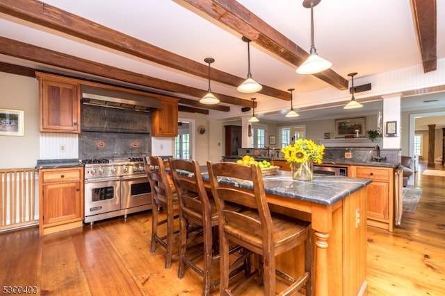 kitchen featuring a breakfast bar area, light hardwood / wood-style flooring, double oven range, backsplash, and a center island