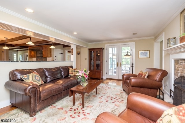 living room with hardwood / wood-style flooring, a stone fireplace, crown molding, and french doors