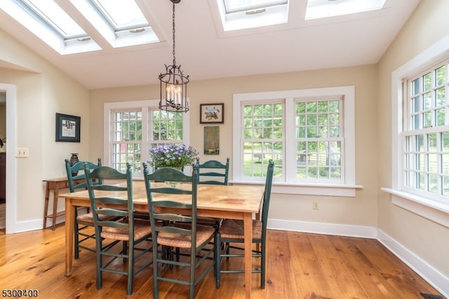 dining area with lofted ceiling with skylight, hardwood / wood-style floors, and a healthy amount of sunlight