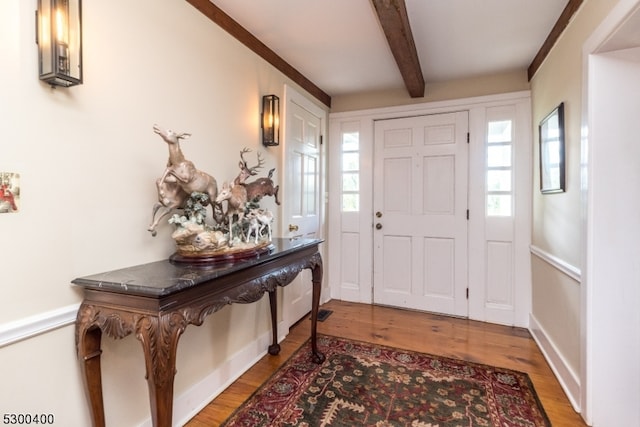 foyer with wood-type flooring and beam ceiling