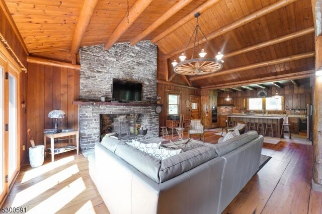 living room featuring wood walls, wood-type flooring, wooden ceiling, and lofted ceiling with beams