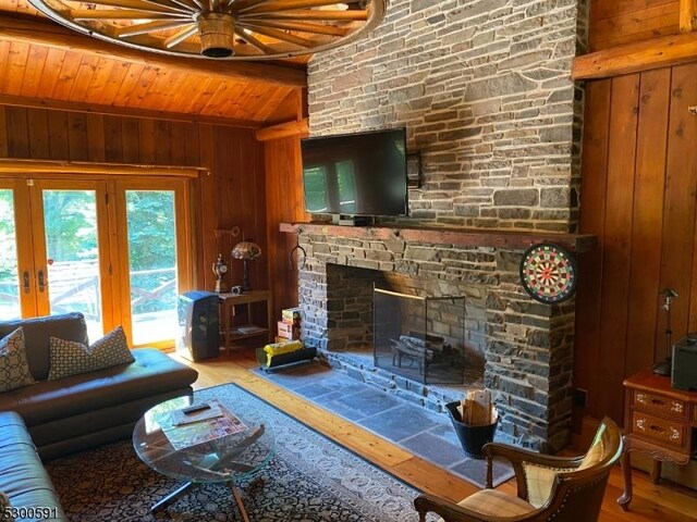 living room featuring a fireplace, wooden ceiling, wooden walls, an inviting chandelier, and light hardwood / wood-style floors