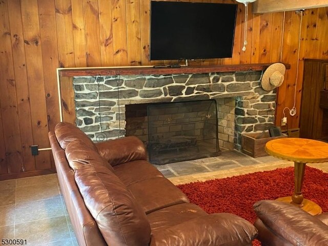 living room with light tile patterned flooring, a fireplace, and wooden walls