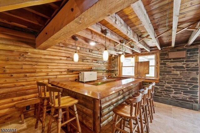 interior space with light tile patterned floors, log walls, beamed ceiling, hanging light fixtures, and wooden ceiling