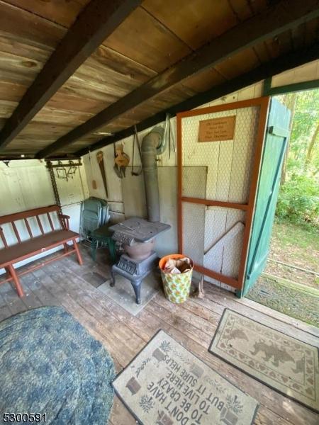 sunroom featuring a wood stove, lofted ceiling, and wood ceiling