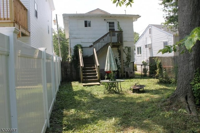 back of property featuring an outdoor fire pit and a yard