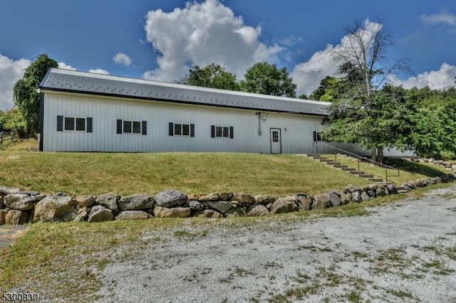 back of house featuring a lawn and metal roof