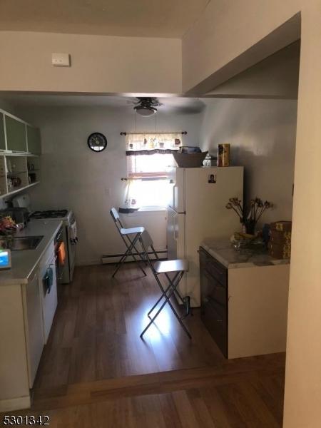 kitchen featuring a baseboard radiator, hardwood / wood-style flooring, sink, and white appliances