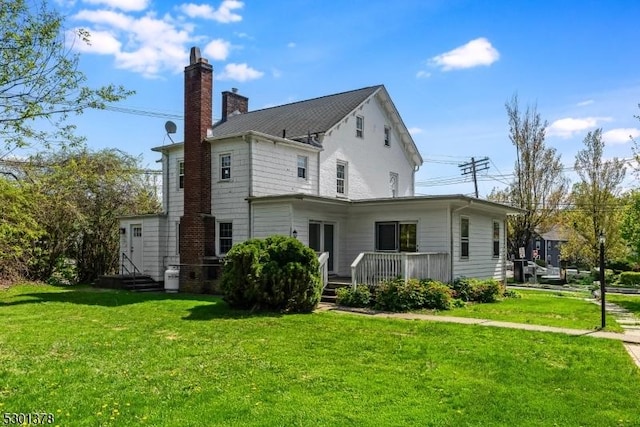 rear view of house with a chimney, a yard, and a deck