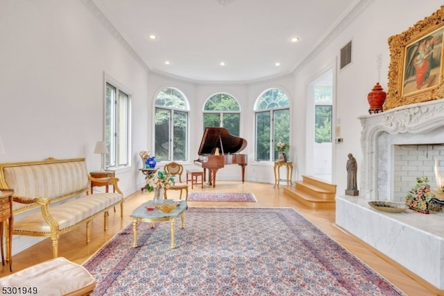 sitting room with a premium fireplace, crown molding, and light hardwood / wood-style floors