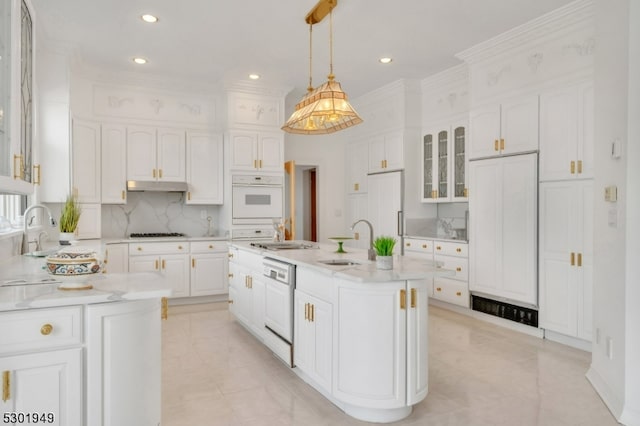 kitchen featuring white appliances, sink, decorative light fixtures, white cabinets, and a kitchen island with sink