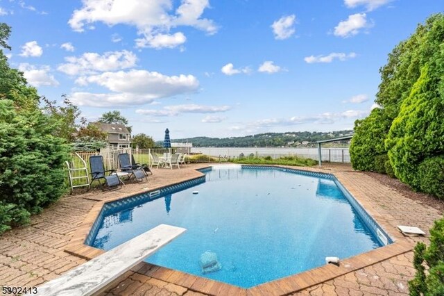 view of swimming pool featuring a diving board and a patio area