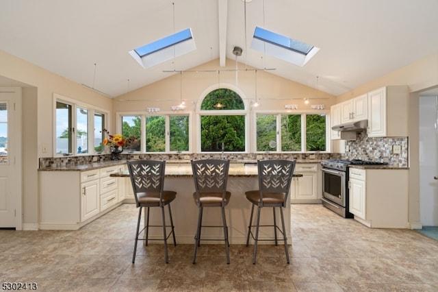 kitchen with a skylight, high end stainless steel range, beam ceiling, and a kitchen island