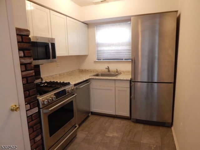 kitchen with white cabinetry, sink, light stone counters, and appliances with stainless steel finishes