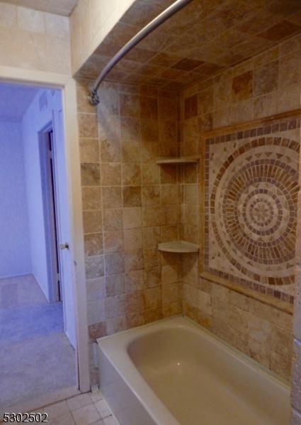 bathroom featuring washtub / shower combination, tile patterned floors, and tile walls