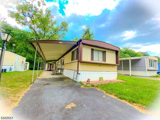 manufactured / mobile home featuring a carport and a front yard