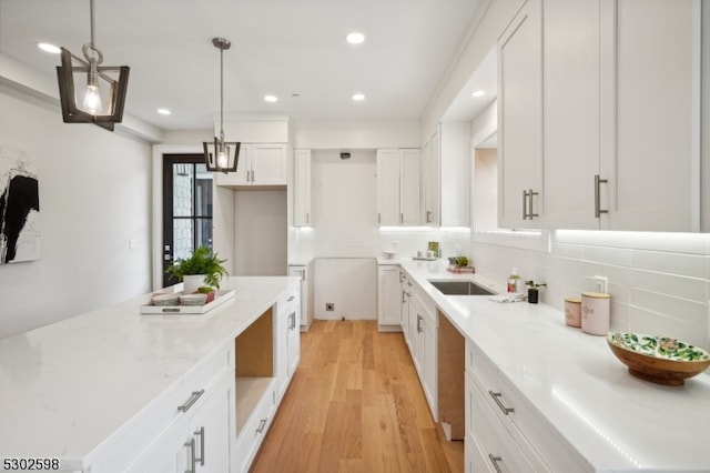 kitchen featuring hanging light fixtures, light stone countertops, white cabinetry, and light hardwood / wood-style flooring