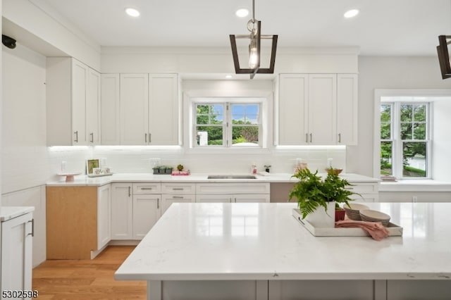 kitchen with white cabinets, a healthy amount of sunlight, pendant lighting, and light hardwood / wood-style flooring