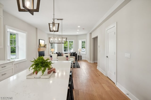 kitchen featuring pendant lighting, light hardwood / wood-style flooring, white cabinetry, and a healthy amount of sunlight