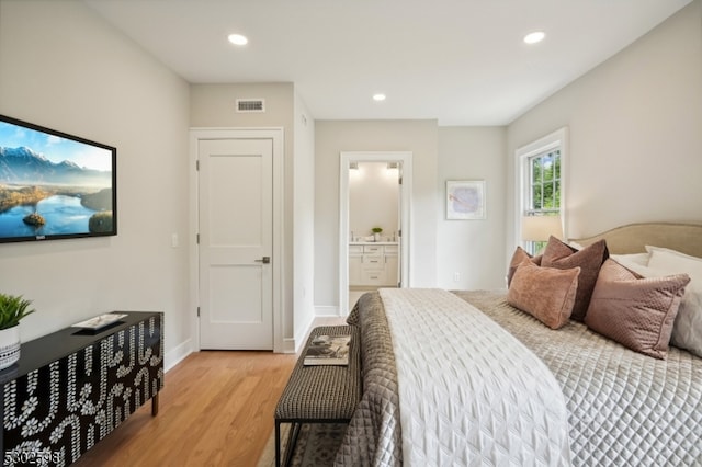 bedroom with ensuite bathroom and light wood-type flooring