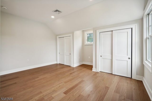 unfurnished bedroom with light wood-type flooring and lofted ceiling