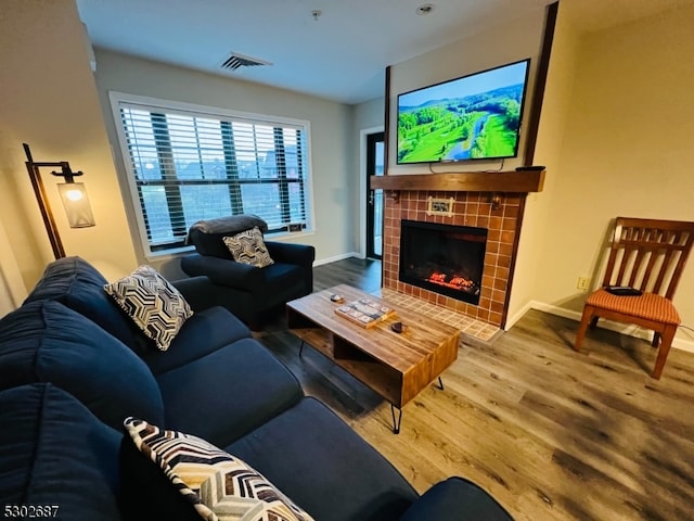 living room with a tile fireplace and hardwood / wood-style floors