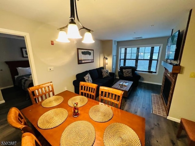 dining area featuring dark hardwood / wood-style flooring, a notable chandelier, and a fireplace