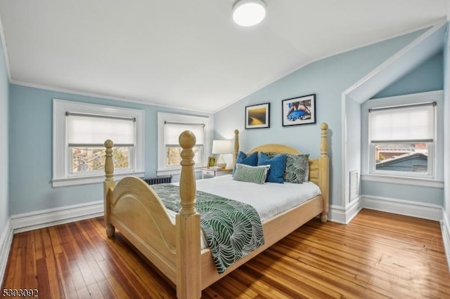 bedroom featuring lofted ceiling, wood-type flooring, multiple windows, and baseboards