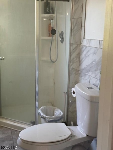 bathroom featuring tile walls, tile patterned flooring, toilet, and walk in shower