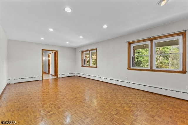 spare room featuring a wealth of natural light, baseboard heating, and light parquet floors