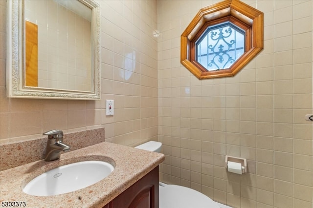 bathroom with vanity, tile walls, and toilet