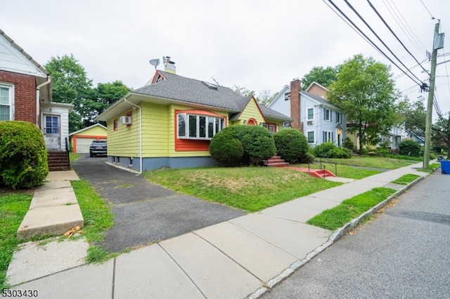 bungalow featuring a wall mounted AC, a garage, and a front lawn