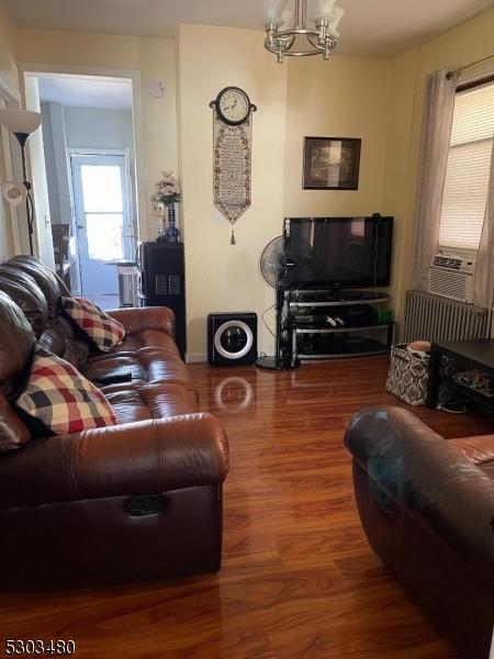 living room with wood-type flooring, radiator, cooling unit, and a chandelier