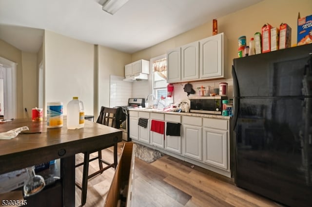 kitchen featuring white cabinetry, tasteful backsplash, light wood-type flooring, appliances with stainless steel finishes, and sink