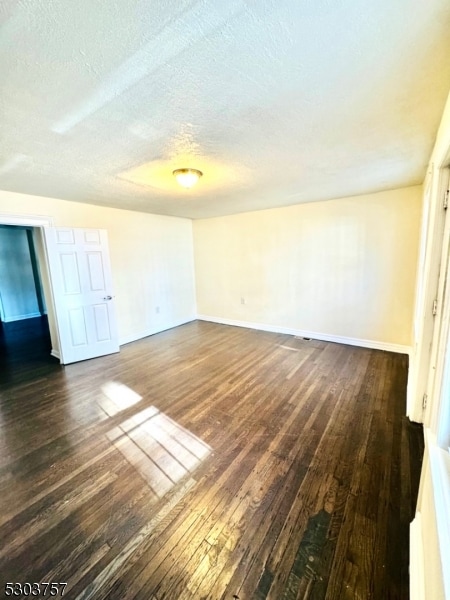 unfurnished room featuring a textured ceiling and dark wood-type flooring