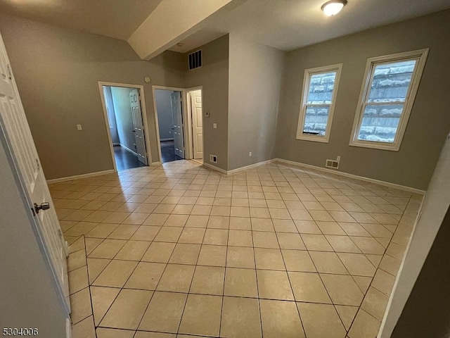 spare room with beam ceiling and light tile patterned floors