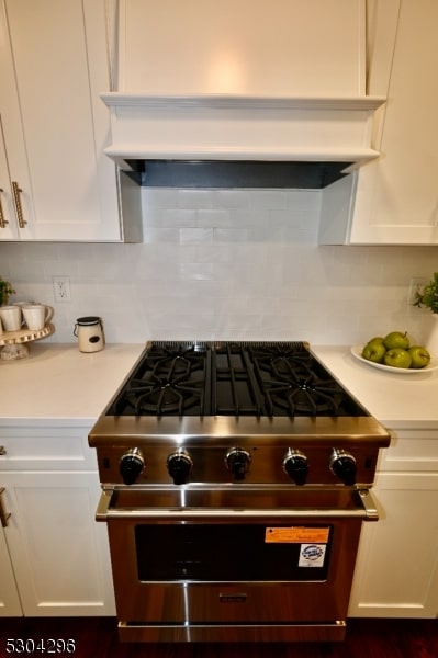 details featuring decorative backsplash, range with gas cooktop, white cabinets, and custom exhaust hood