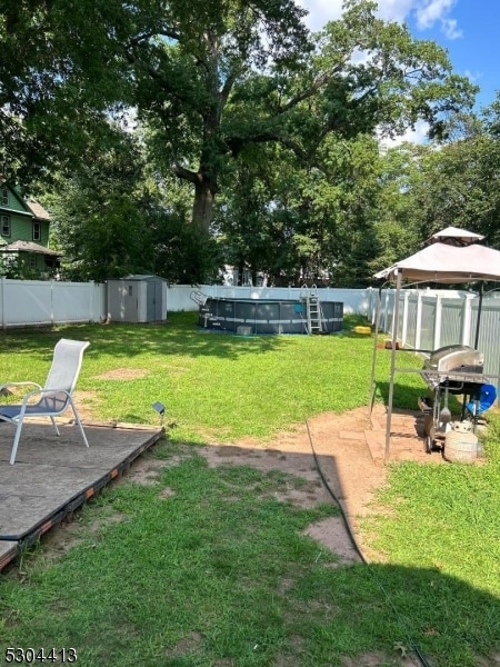 view of yard featuring a fenced in pool and a storage unit