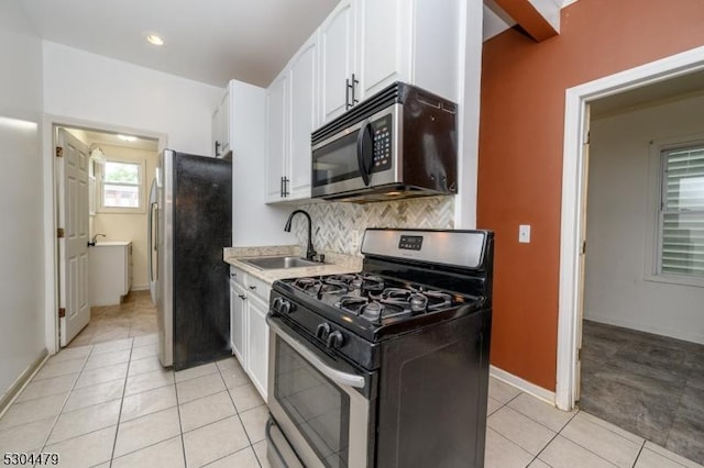 kitchen with white cabinetry, sink, backsplash, light tile patterned flooring, and appliances with stainless steel finishes