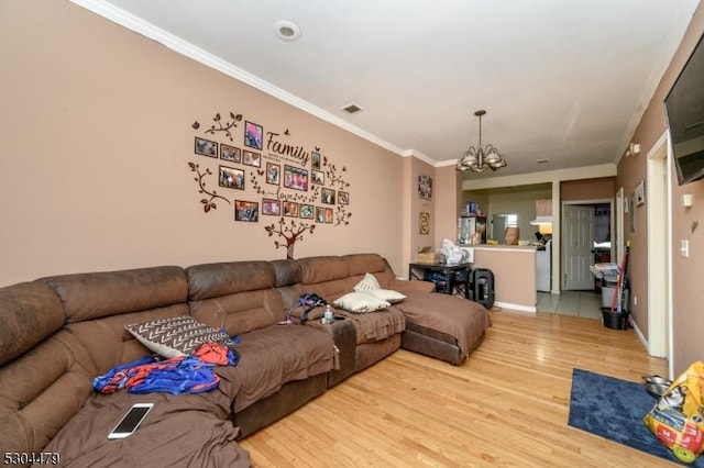 living room featuring crown molding, light hardwood / wood-style flooring, and a notable chandelier