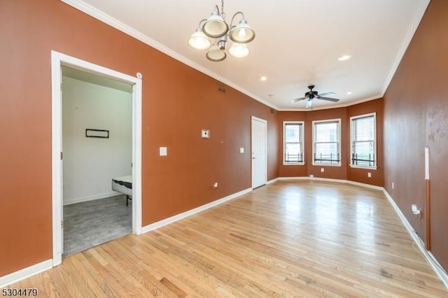 unfurnished room featuring ceiling fan with notable chandelier, light wood-type flooring, and crown molding