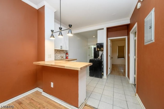 kitchen featuring white cabinets, kitchen peninsula, decorative backsplash, decorative light fixtures, and butcher block counters