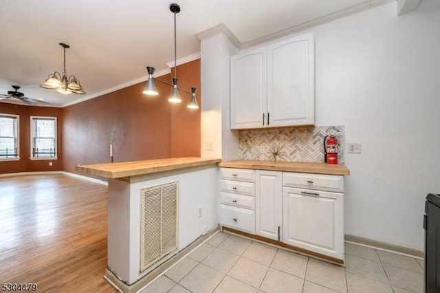 kitchen featuring kitchen peninsula, white cabinets, hanging light fixtures, and ceiling fan with notable chandelier