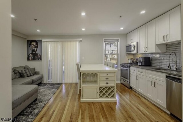 kitchen featuring sink, light hardwood / wood-style flooring, stainless steel appliances, and white cabinets