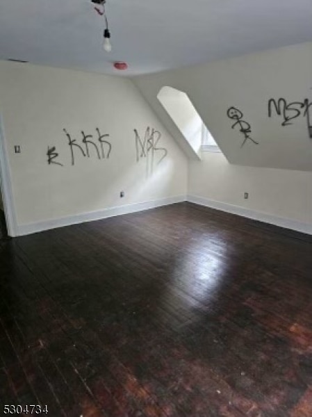 interior space with vaulted ceiling with skylight and wood-type flooring